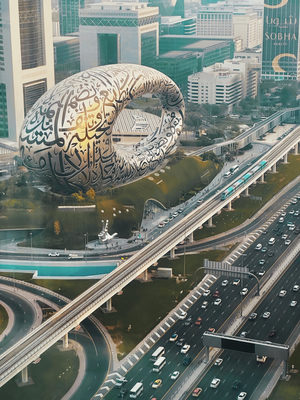 Aerial view of Museum of the Future, Dubai, with busy roads and modern buildings surrounding it.